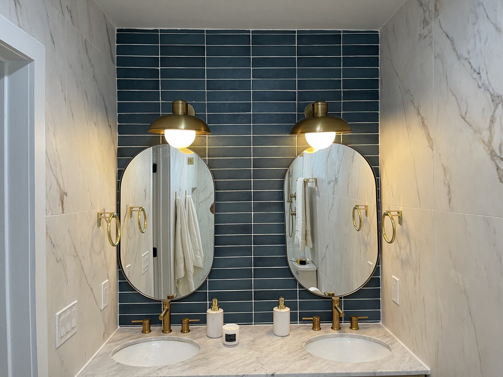 Double vanity bathroom with teal tile and brass sconces