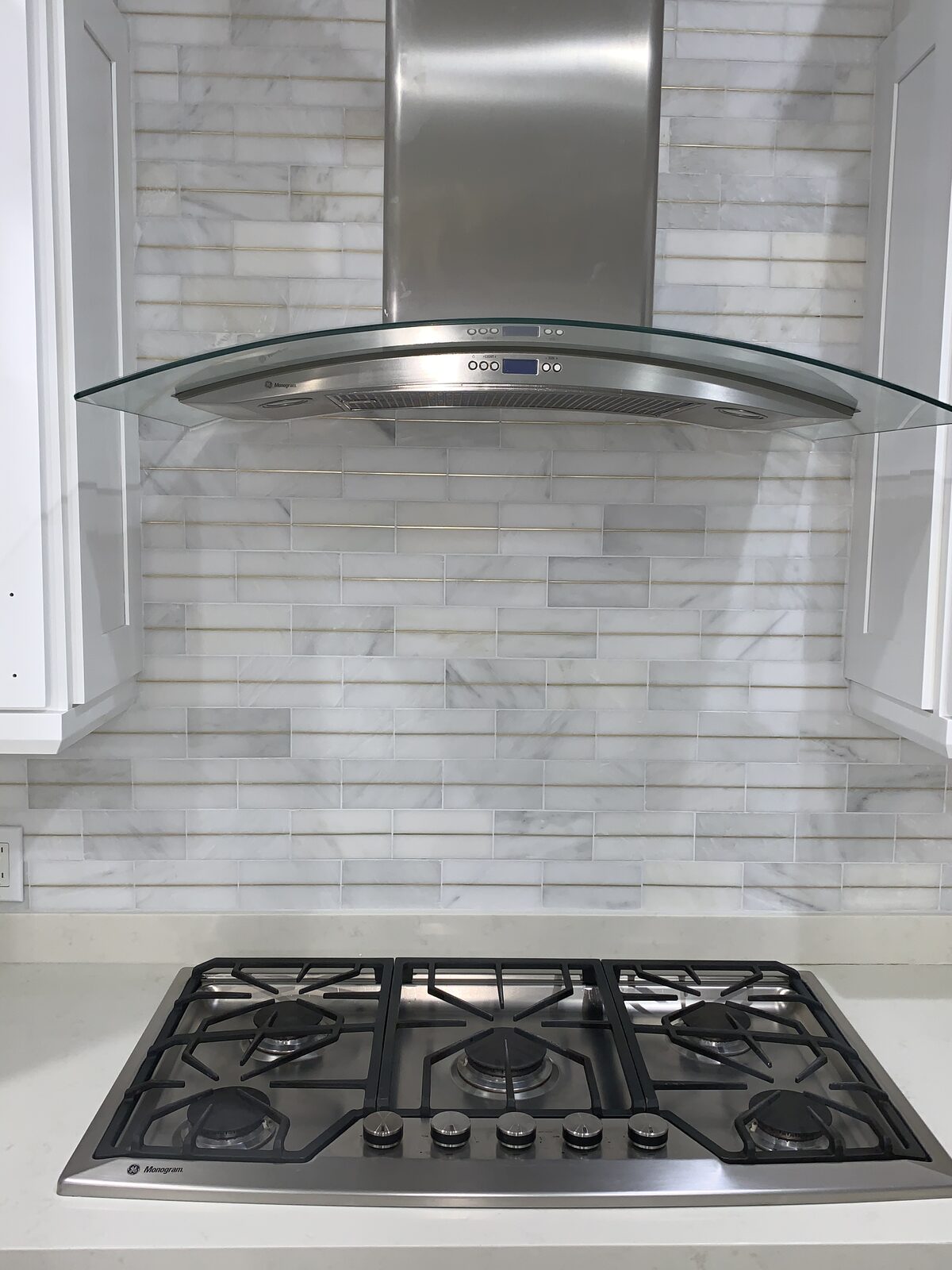 Gas range with stainless hood and marble backsplash